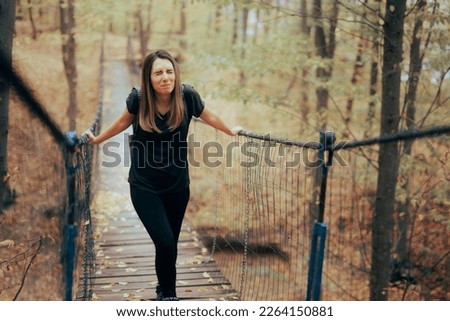 
Anxious Woman Afraid of Heights Crossing a Bridge. Stressed travel girl suffering from acrophobia conquering her fears
