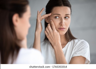 Anxious Young Woman Look In The Mirror Worried About Wrinkle Or Acne On Unhealthy Skin, Upset Unhappy Millennial Female Examine Squeeze Pimple On Face, Cosmetology, Skincare Concept