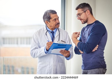 Any questions regarding the medication. Shot of a confident mature male doctor consulting a patient while standing inside a hospital during the day. - Powered by Shutterstock