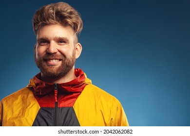Any weather is okay concept. Emotive portrait of laughing charismatic muscular 30-year-old man standing over blue background. Stylish haircut. Colourful jacket. Copy-space. Close up. Studio shot