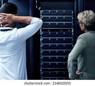 Anybody Know A Good IT Guru. Rearview Shot Of Two Technicians Looking Stressed While Working In A Data Centre.