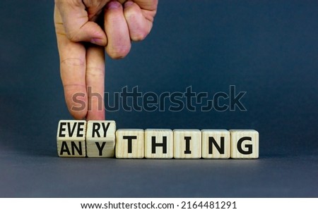 Anything or everything symbol. Businessman turns cubes and changes the concept word Anything to Everything. Beautiful grey background. Business motivational anything or everything concept. Copy space.