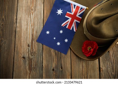 Anzac army slouch hat with Australian Flag and Poppy on wooden background