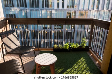 Apartment Balcony In City With Grass Turf And Potted Plants. Evening Light.