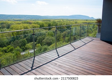 Apartment balcony scenery view with exotic grooved cumaru wood decking and modern glass railing - Shutterstock ID 2117500823