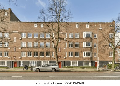 an apartment building with cars parked on the side of the street in front of it and trees lining the street - Powered by Shutterstock
