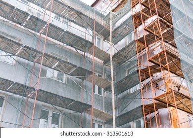 Apartment Building Exterior Under Renovation With Scaffolding And Green Netting