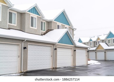 Apartment Building Exterior With White Garages And Pitched Roofs Against Sky