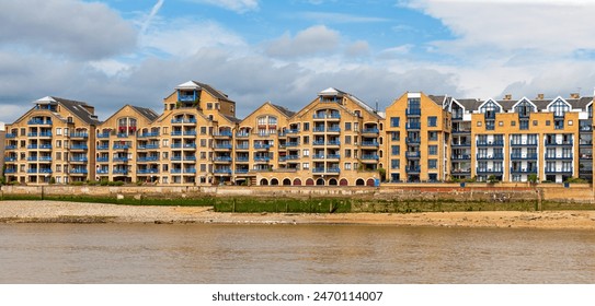 Apartment complex facing river Thames. Series of brown and blue houses at Wapping High Street, Wapping, London, United Kingdom.