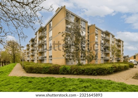 an apartment complex with green grass and trees in the foreground, on a bright sunny day - stock photo
