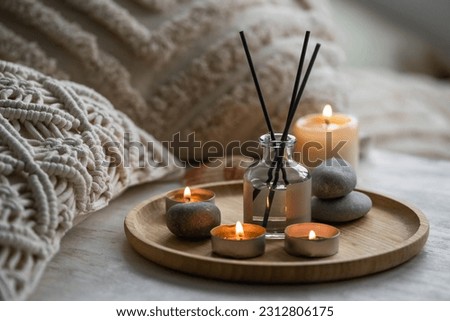 Apartment natural aroma diffusor with sea breeze fragrance. Burning candles on bamboo tray, cozy home atmosphere. Relaxation, detention zone in the living or bedroom. Stones as decor