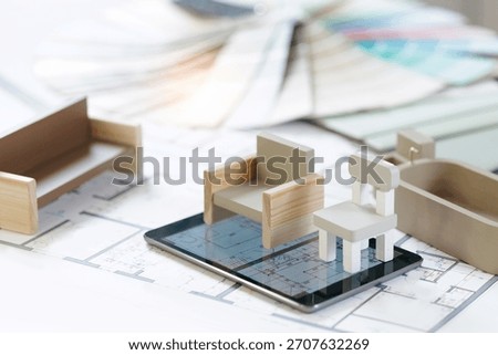 Apartment plan Interior design concept with miniature furniture and floor plans on digital tablet screen.