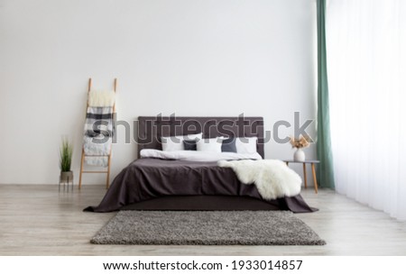 Apartment in simple minimalist Scandinavian design and home interior with furniture. Bed for two with blanket and pillows, stairs, dry plants in vase on gray wall background in modern bedroom, nobody