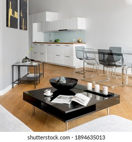 Apartment With White Kitchen With Transparent Dining Table With Chairs Open To Living Room With Black Square Coffee Table