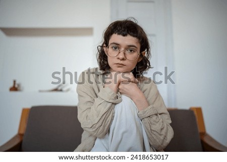 Apathetical teenager in deep thoughts, looking at camera with indifferent glance, feeling melancholy, doldrums, depression, grief, heart break, sadness. Puberty, negative emotional adolescence period