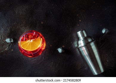 Aperol Cocktail With A Fresh Orange Slice And A Shaker, Italian Summer Cold Drink, Overhead Flat Lay Shot With A Place For Text, On A Black Slate Background