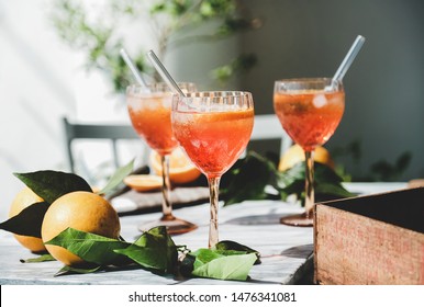 Aperol Spritz aperitif alcohol cocktail in glasses with fresh oranges and ice on grey marble board, selective focus, close-up. Summer refreshing drink concept