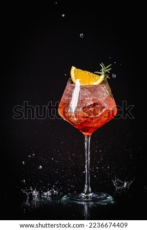 Aperol spritz cocktail in a glass with ice and orange on a black background