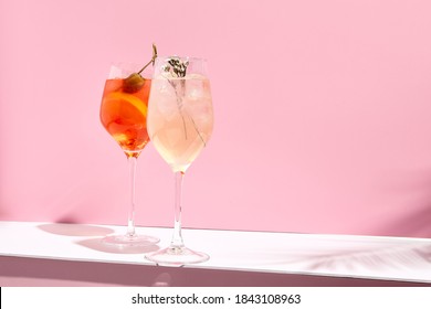 Aperol Spritz Cocktail auf rosafarbenem Hintergrund. Sonnenlicht und Schattenhintergrund. Rosa und weiß minimalistisch