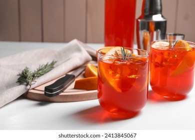 Aperol spritz cocktail, rosemary and orange slices on white wooden table