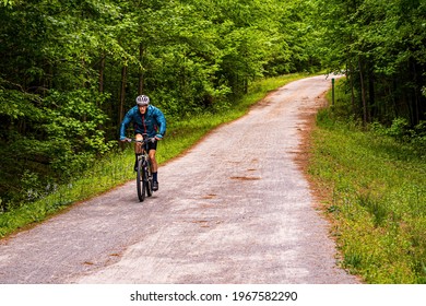 Apex, North Carolina USA-04 28 2021: A Man In A Blue Jacket Rides His Road Bike On The American Tobacco Trail In Wake County.