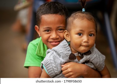 Apia / Western Samoa - April 21, 2013: A young Samoan Boy holds his little sister close and smiles for a picture in Apia, Western Samoa.