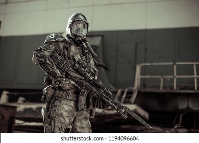 Apocalypse. An Armed Man In Chemical Protection Stands Near An Iron Structure.