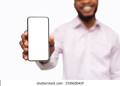 App for your business. Smartphone with blank screen in hands of unrecognizable smiling black man, selective focus on phone, closeup
