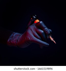 Apparel for tattoos in hands in gloves on a black background. Close-up is stylish. Tool apparatus machine master artist. Profession tattooer. The needle hurts the danger of AIDS infection. Permanent