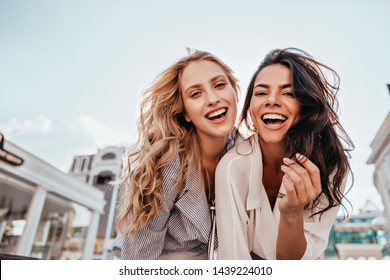 Appealing long-haired girls posing on sky background. Laughing ladies enjoying weekend together.