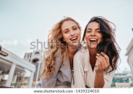 Appealing long-haired girls posing on sky background. Laughing ladies enjoying weekend together.