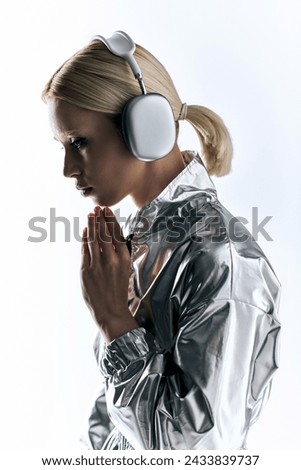 appealing peculiar female model with headphones wearing silver robotic attire and enjoying music