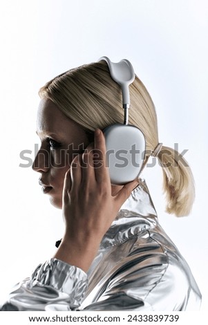 appealing peculiar female model with headphones wearing silver robotic attire and enjoying music