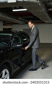 appealing red haired man in smart suit getting into his car on parking lot, business concept