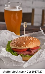 Appetizer For Beer. Homemade Burger Stuffed With Dried Red Fish, Tomato, Onion, Pickled Cucumber, Lettuce Leaves In Paper On A Plate Close-up. Fast Food. Vertical Orientation, Copy Space, No People