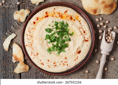 Appetizer creamy hummus tasty traditional food with tahini paste, olive oil, paprika and parsley in rustic plate on vintage wooden background - Powered by Shutterstock