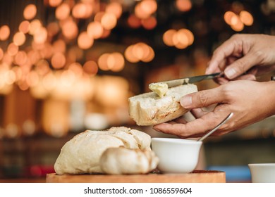 Appetizer food ; Bread and butter serve on wooden plate. Male use the knife and butter to prepare food