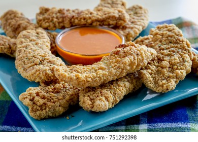 Appetizer Of Fried Chicken Strips On Blue Square Plate With Hot Buffalo Wing Dipping Sauce In Center