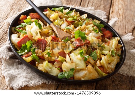 Appetizer of fried white cabbage with bacon closeup on a plate on a wooden table. horizontal
