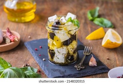 Appetizer, marinated feta with spices and olives in oil in a glass jar on a wooden background. Cheese Appetizer Recipes - Powered by Shutterstock