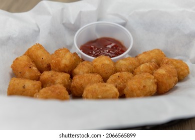 Appetizer order of a basket of crispy tator tots complete with ketchup dipping sauce. - Shutterstock ID 2066565899