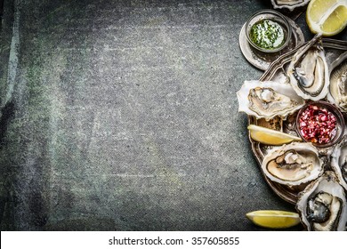 Appetizer Oysters plate with lemon and sauces on rustic background, place for text