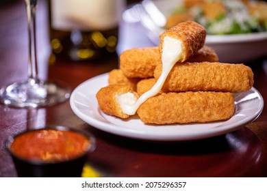 appetizer shareable starter small white saucer plate six deep-fried cheesy mozzarella sticks red pomodoro marinara dipping sauce rustic wooden dining table white wine glass bottle side dishes