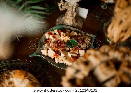 Appetizer or snack items presented on a distinctive decorative, leaf-shaped serving platter, set against a background suggesting a catering event.