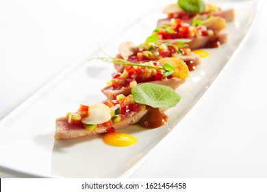 Appetizer With Tuna Tartar, Seasonal Vegetables And Greens On White Restaurant Plate Isolated. Macro Photo Of Delicious Healthy Red Fish Tatar Or Tar-tar Entree Closeup