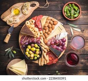 Appetizers boards with assorted  delicatessen cheese, salami, grape and nuts. Charcuterie and cheese platter, Spanish style and ingredients: olives, Pimientos, Chorizo, picos, cheese Semicurado  - Shutterstock ID 2238450391