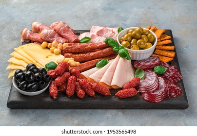 Appetizers boards, meat and cheese slicing with basil and olives on a rectangular board on a gray background. Side view. - Powered by Shutterstock