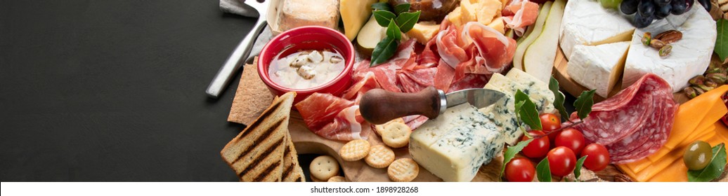 Appetizers Table. Cheese, Fuits And Meat Board On Dark  Background. Copy Space, Panorama