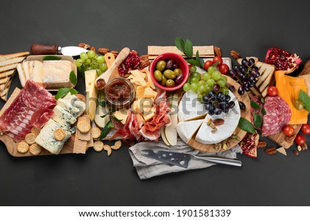 Appetizers table. Cheese, fuits and meat board on dark  background. Top view with copy space