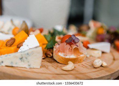 Appetizers table. Cheese and meat variety board over wooden tray - Shutterstock ID 1336433672